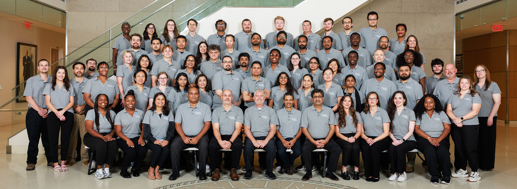 Group portrait of members of the Department of Cell and Molecular Biology inside the School of Medicine lobby. There is a stairase behind them.